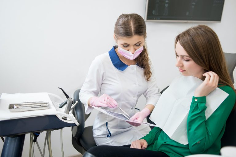 Dentist explaining the details of x-ray image to patient in dental office. Dentistry