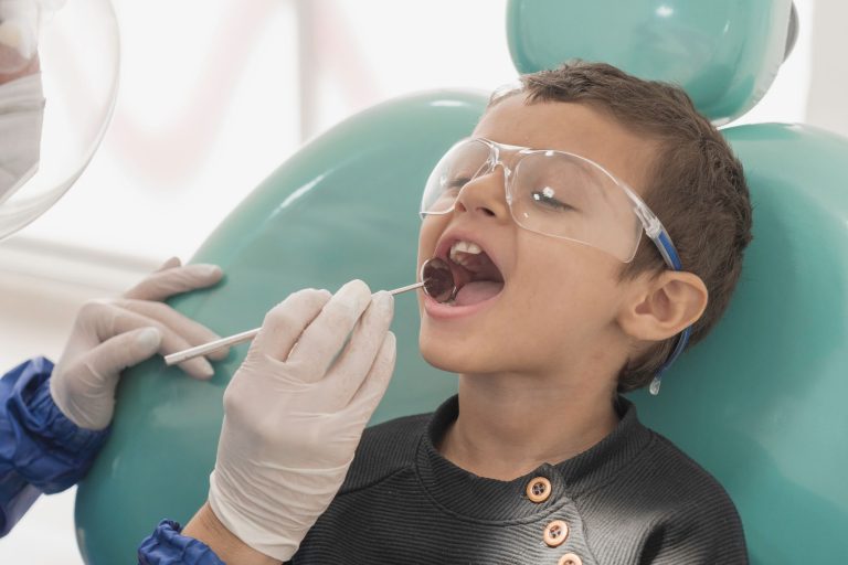 Toddler boy getting his teeth checked by a dentist in a the dental clinic