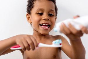 adorable african-american kid applying tooth paste on brush