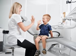 Happy kid at dentist office giving high five to a dentist