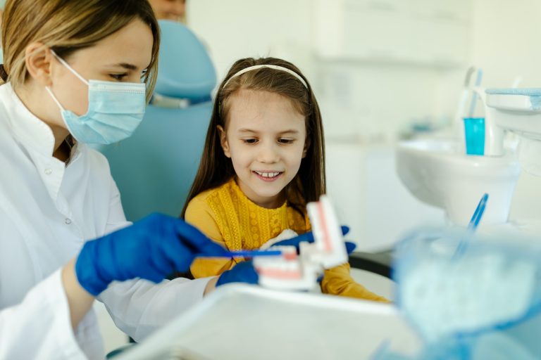 Oral hygienist with jaw model teaching patients to brush teeth properly.