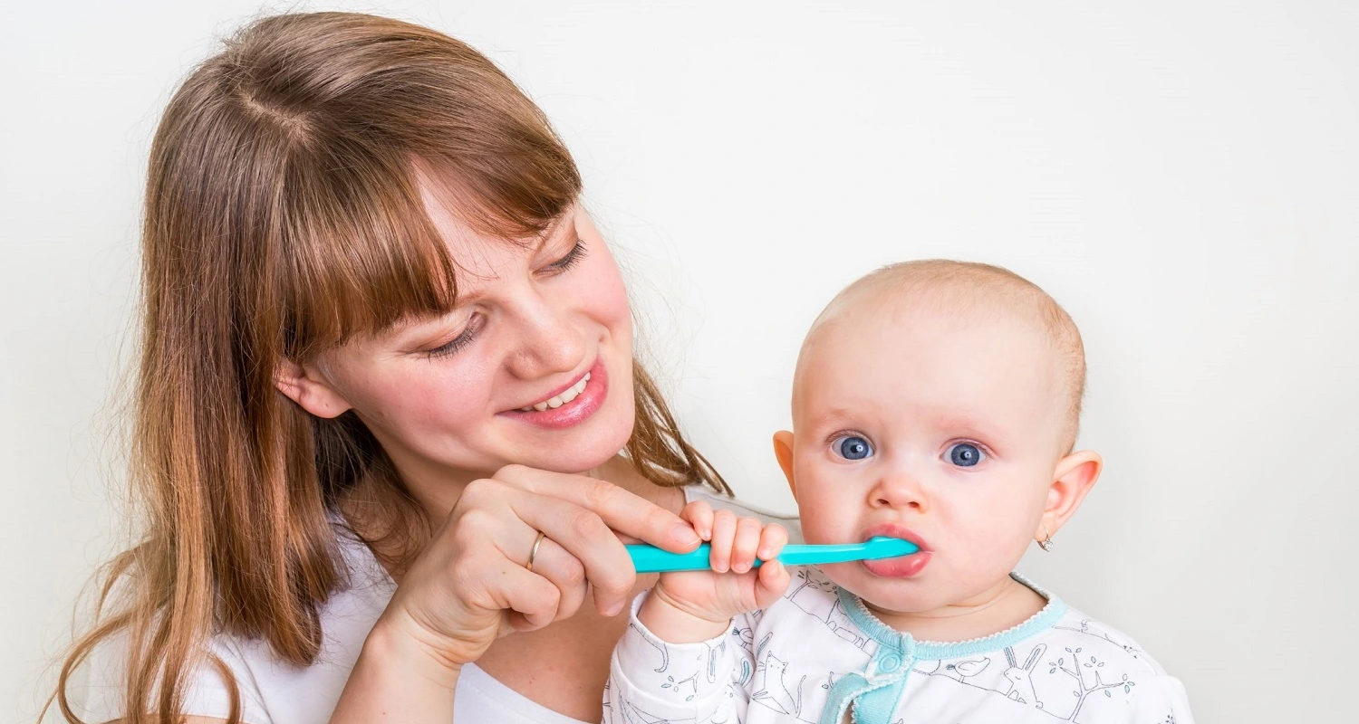 mother brushing baby's teeth