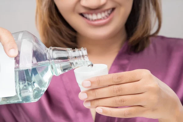 a lady using mouthwash